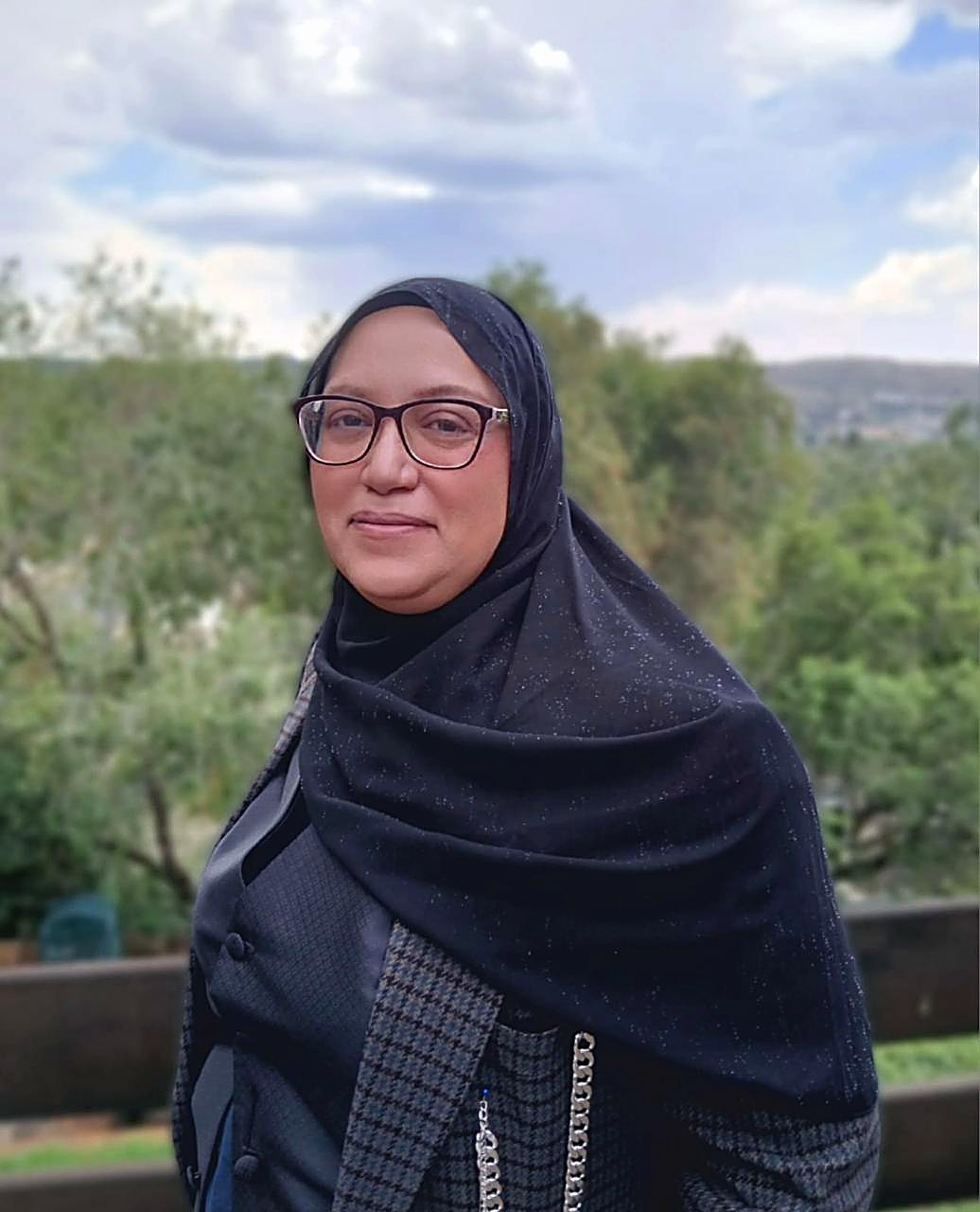 Fatima, book doula, smiling with trees behind her