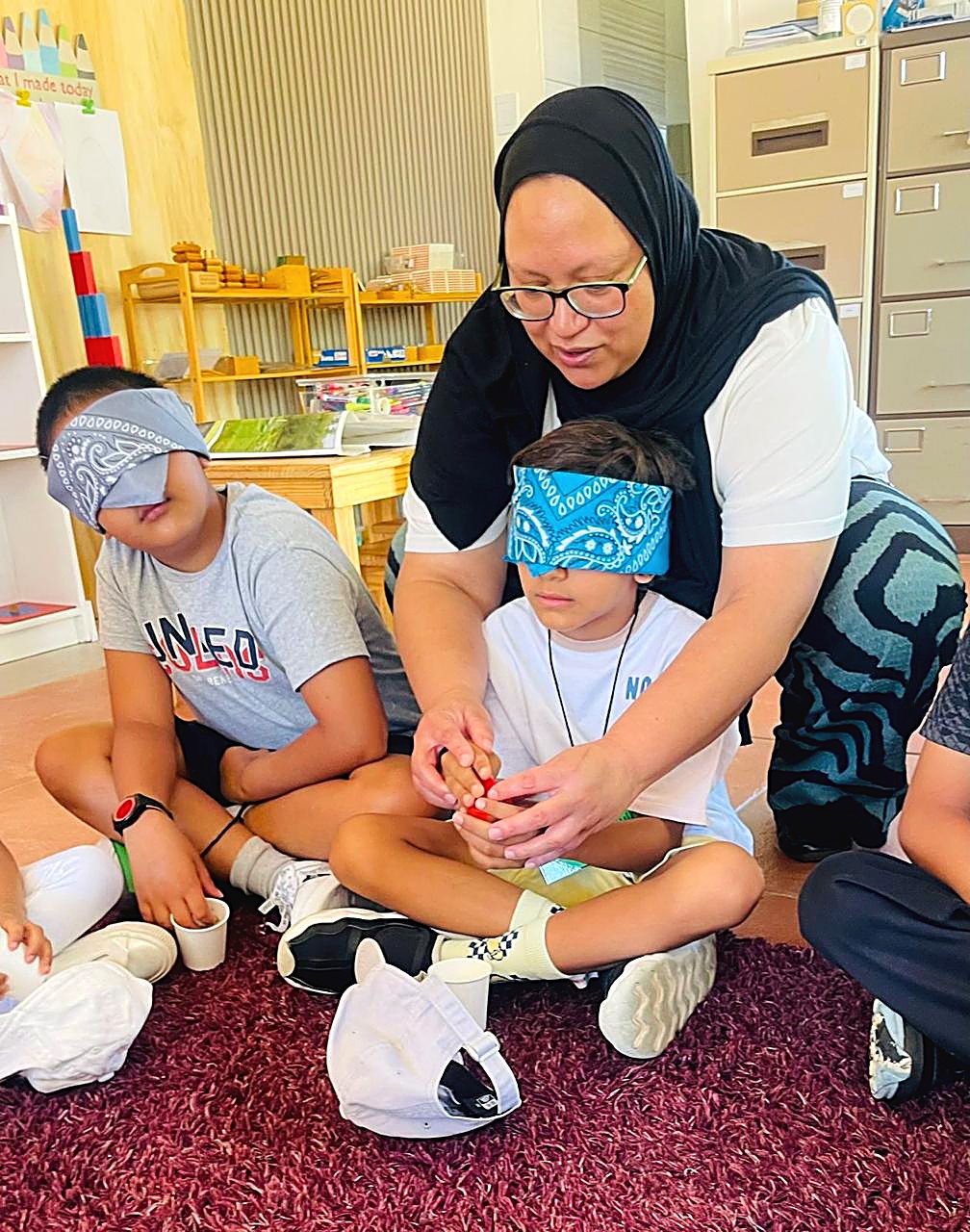 Fatima guiding children through a blindfolded sensory play activity