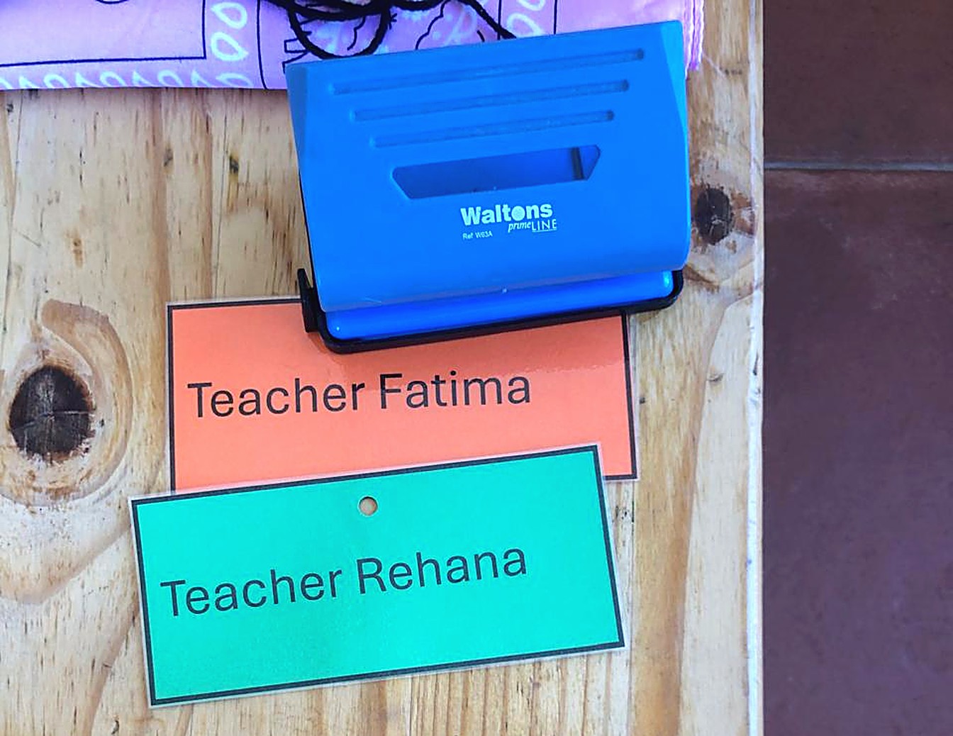 A name tag reading Teacher Fatima on a wooden table